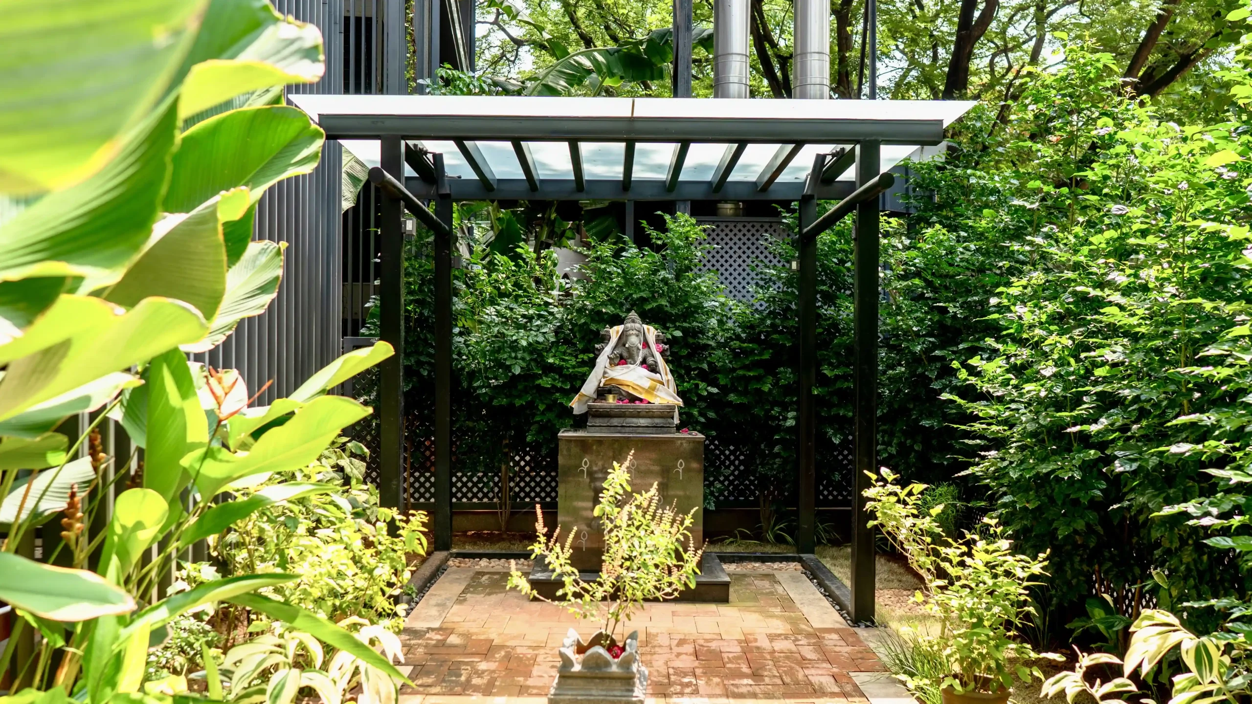 Landscaping work by kaizen | Garden shrine with statue amid greenery.